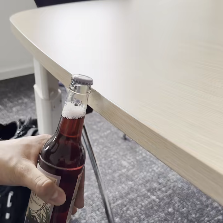 Eine Flasche wird mit der Tischkante geöffnet
