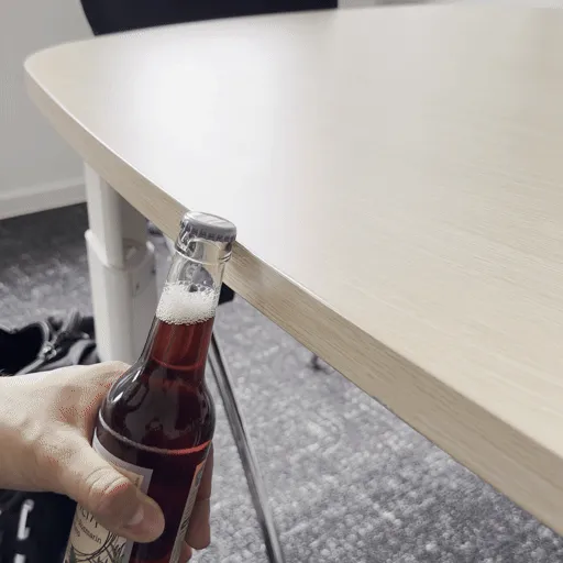 Eine Flasche wird mit der Tischkante geöffnet